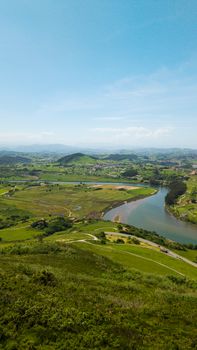 Scenic aerial view of lush green countryside with a winding river in Spain under a clear blue sky.