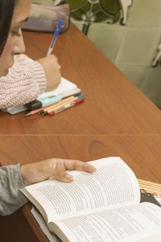 Two students read and write attentively at a wooden desk in a Montevideo classroom.