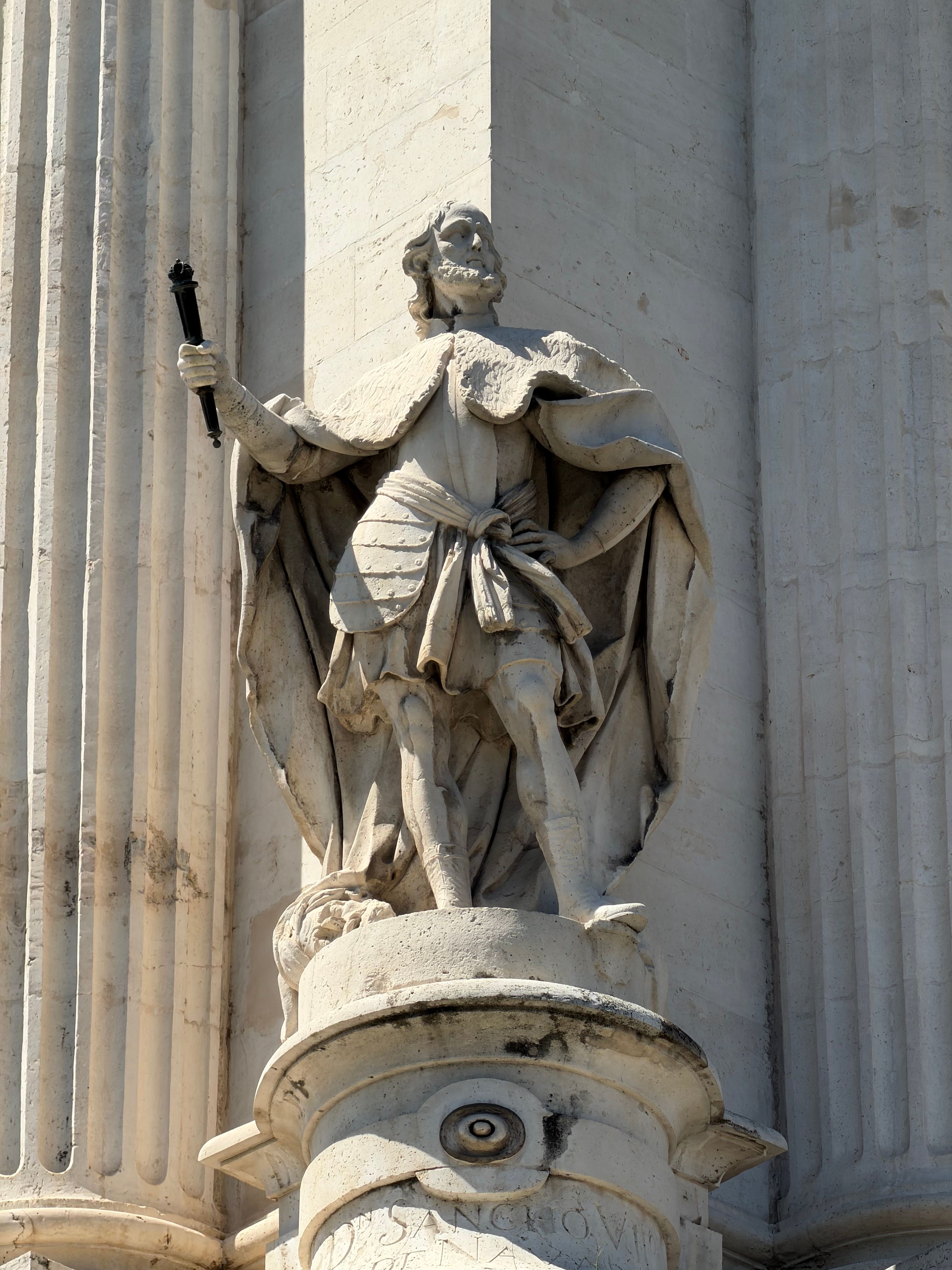 Detailed stone statue of a historical figure on a landmark building facade in Madrid.