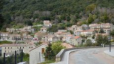 Scenic view of traditional stone houses in Levie, nestled among lush greenery.