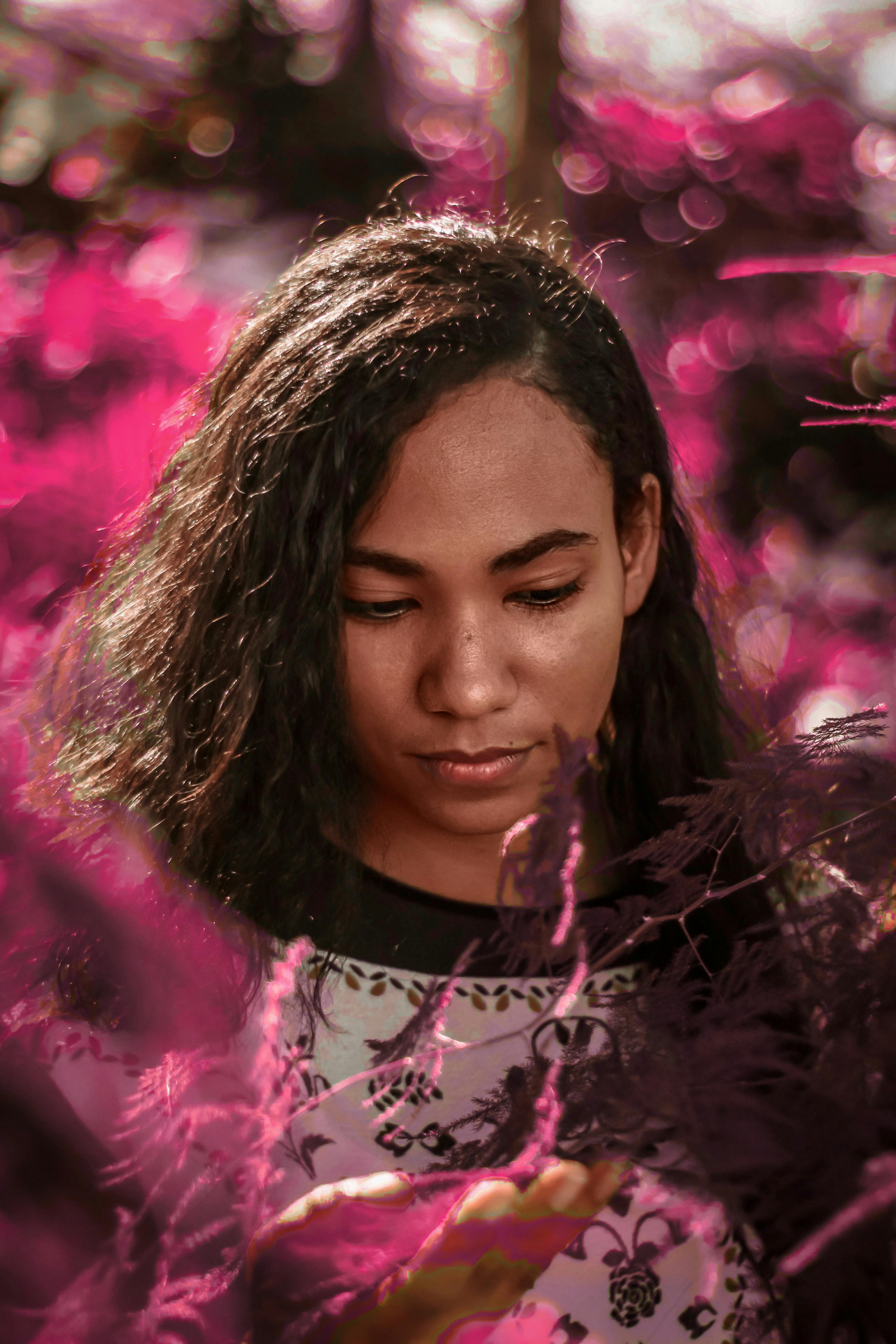 一位年轻女子的肖像被充满活力的粉红色树叶环绕，画面着重展现她的表情与时尚风格