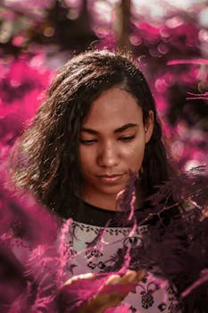 一位年轻女子的肖像被充满活力的粉红色树叶环绕，画面着重展现她的表情与时尚风格