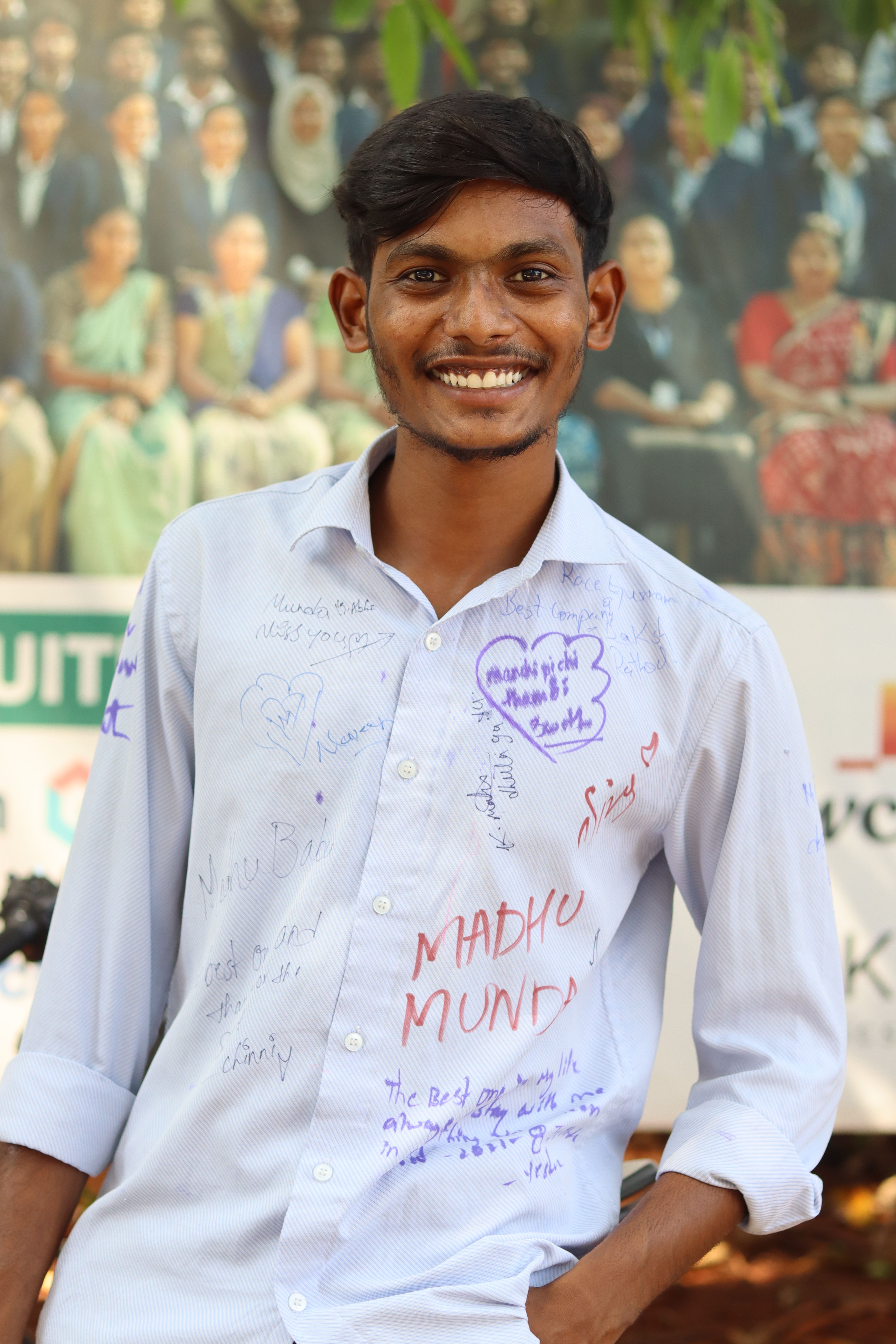 A young man smiles in front of a blurred crowd with an autographed shirt.
