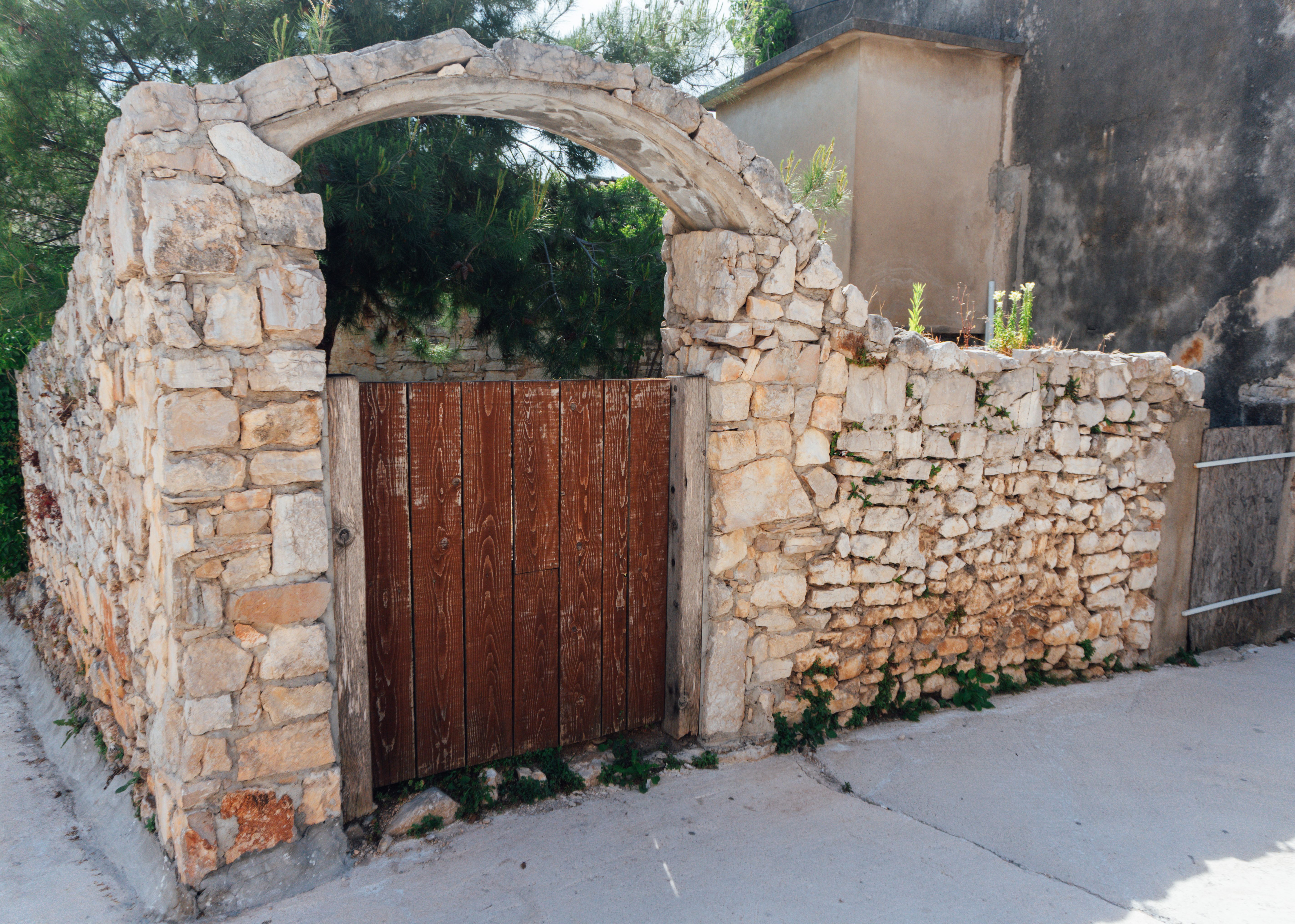 Rustic Stone Archway with Wooden Gate Outdoors · Free Stock Photo