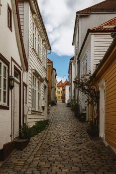 A picturesque cobblestone street flanked by traditional wooden houses in a historic Norwegian town.