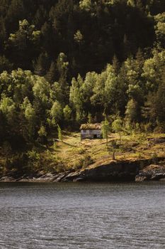 Idyllic cabin by a lakeside in Norway, surrounded by lush forest.