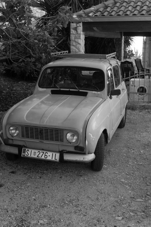 Free Black and white photo of a vintage Renault car parked in a rustic outdoor setting. Stock Photo