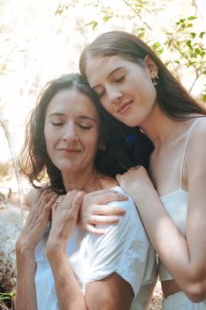 Two women sharing a heartfelt embrace in a serene outdoor setting, expressing love and connection.