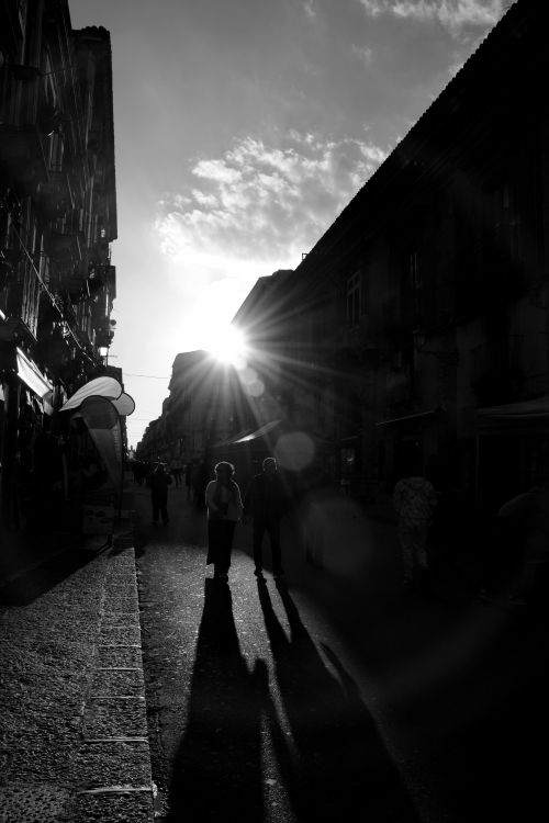 Free Silhouettes of people walking along a street against the dramatic setting sun. Stock Photo