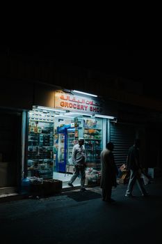 People walking outside a grocery shop at night in Muscat, Oman, capturing local daily life.