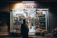 A local stands outside a grocery shop at night in Muttrah, Muscat showcasing daily life in Oman.