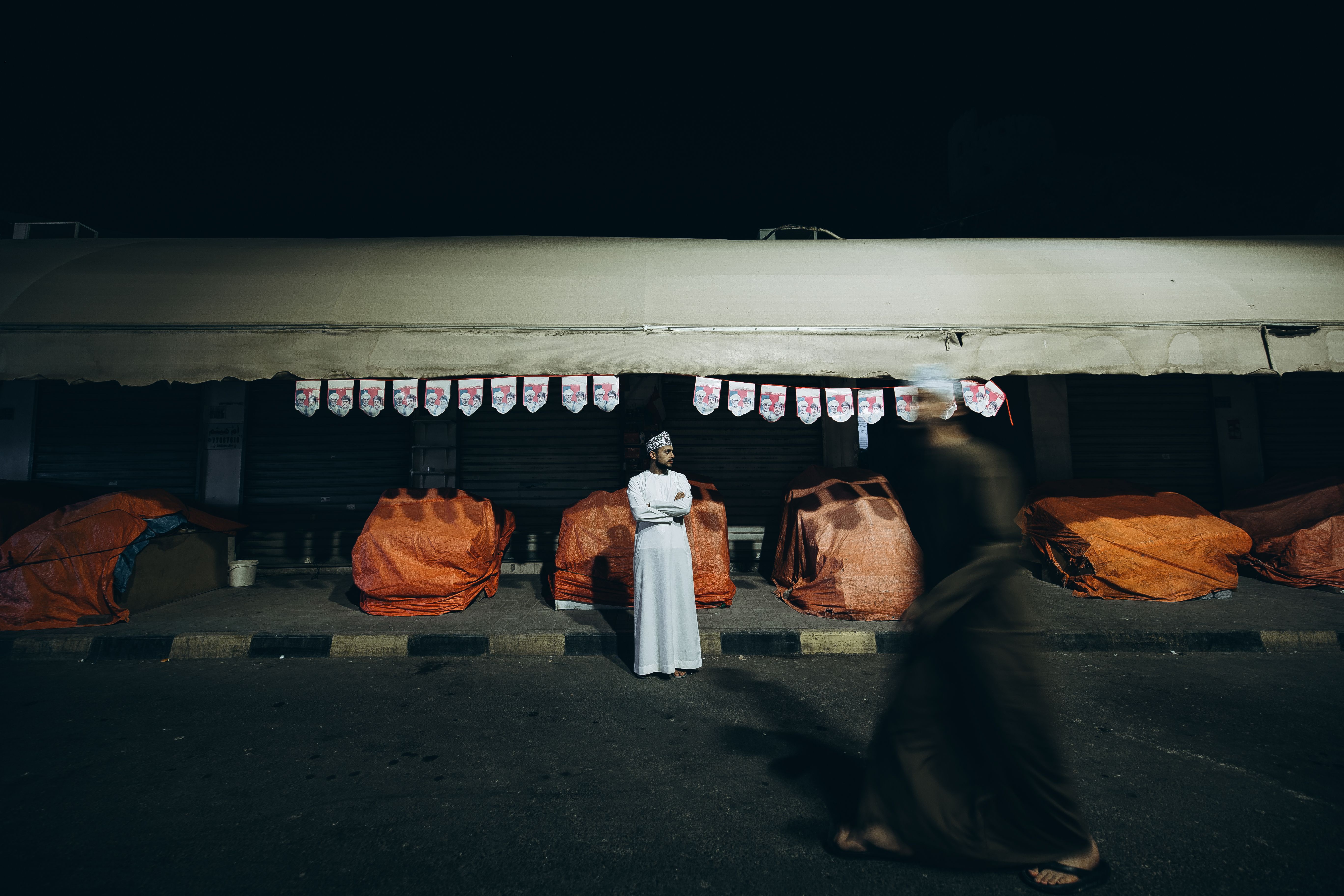 A nighttime moment captured at Muttrah Souq in Muscat, highlighting street life and cultural attire.