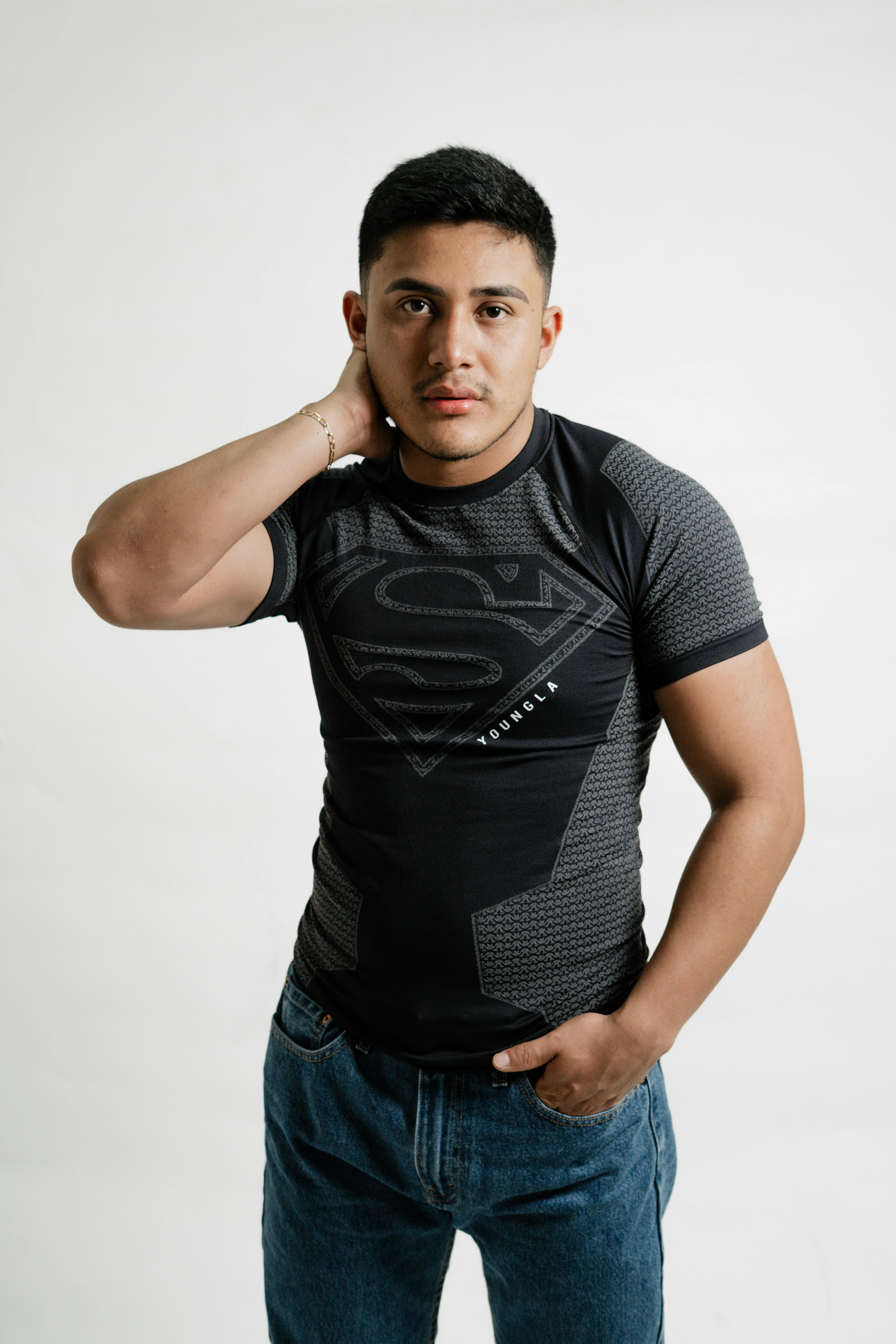 Young man in a superhero-themed shirt posing confidently in a studio setting.