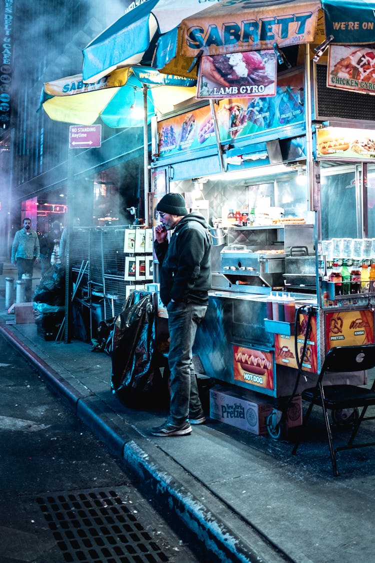 Man Standing In Front Of A Food Stall