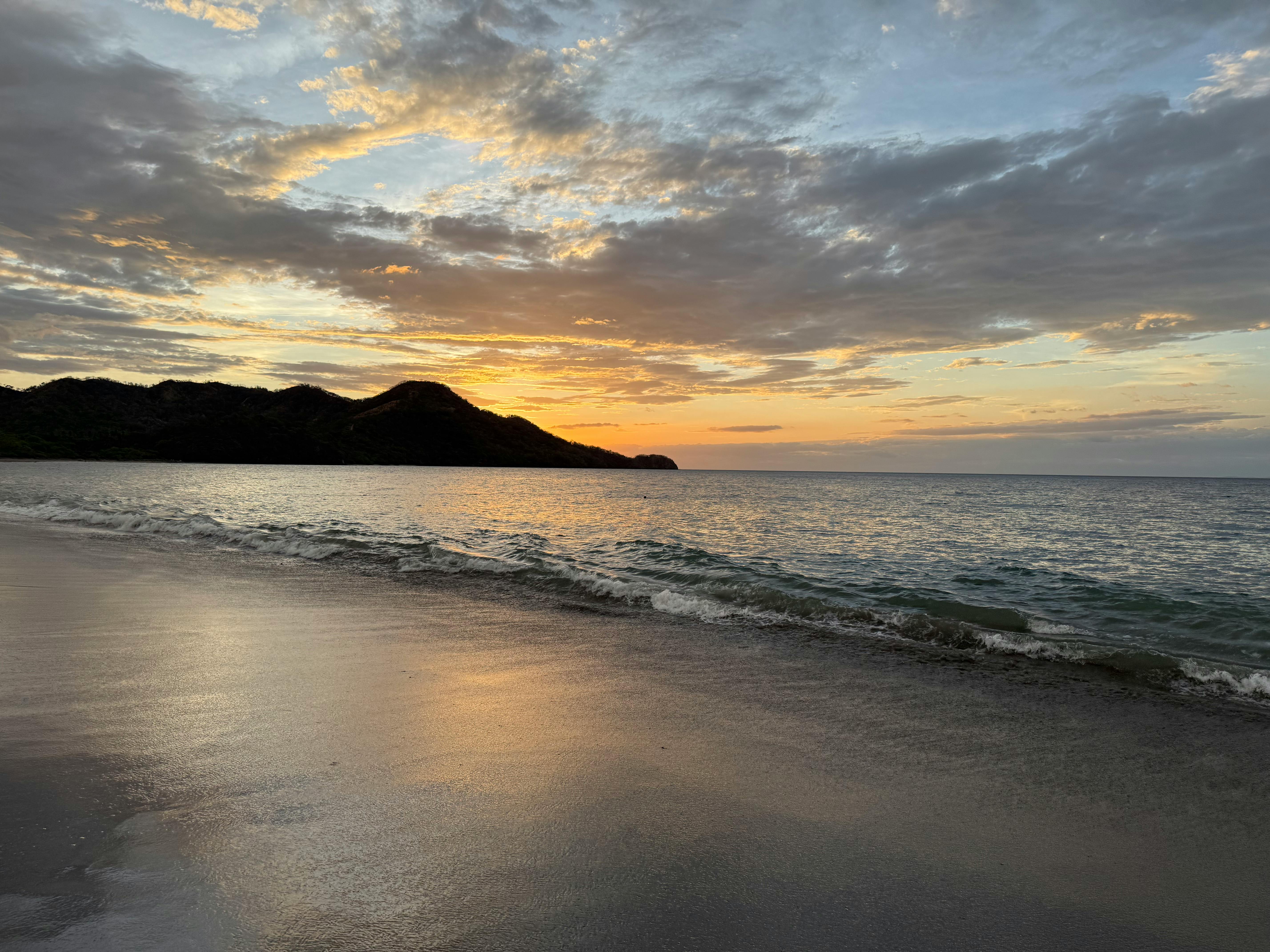 Serene sunset over a tranquil Costa Rican beach with vibrant skies and gentle waves.