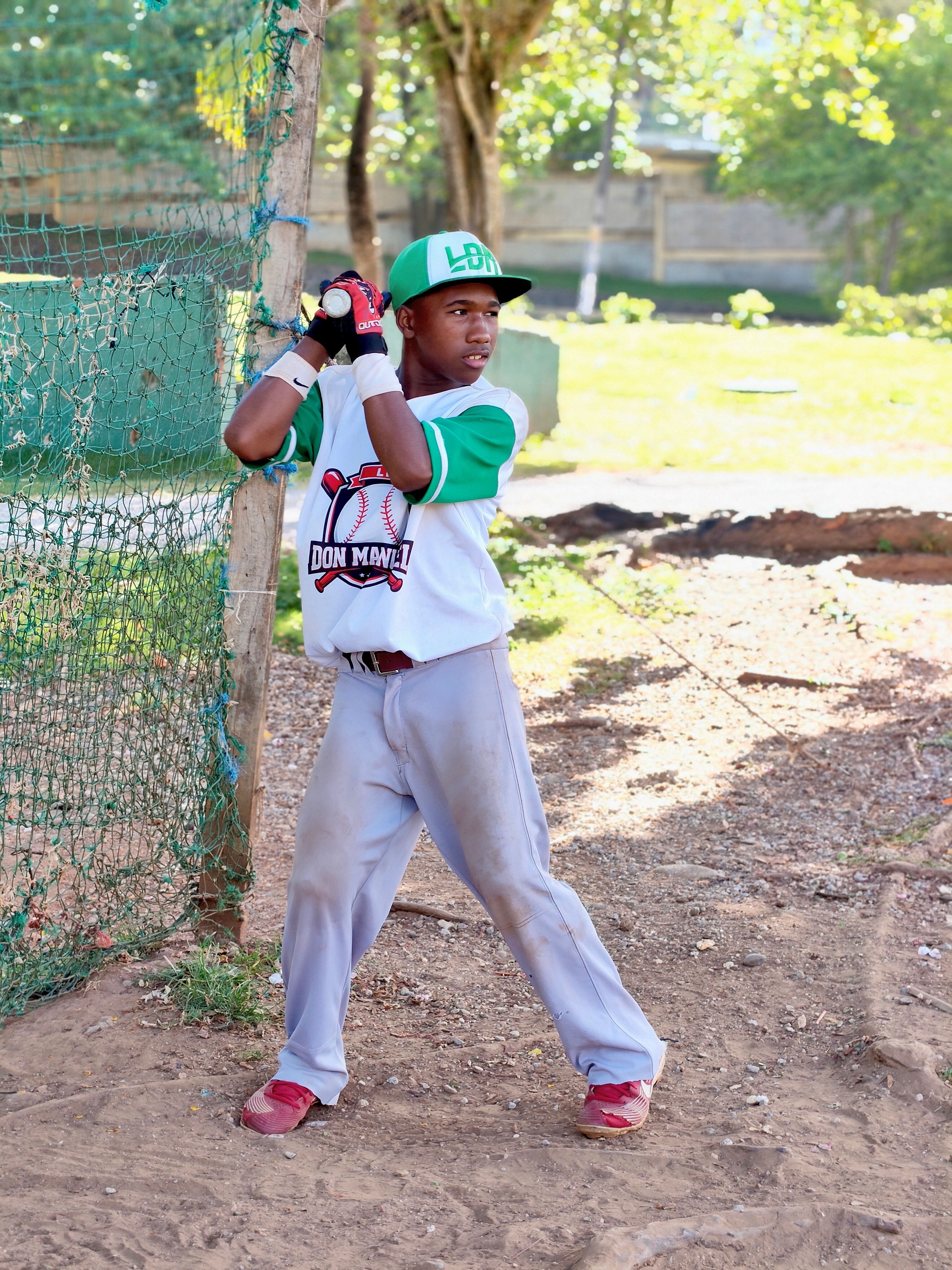 A young baseball player gets ready to swing the bat during practice on a sunny day at an outdoor field.