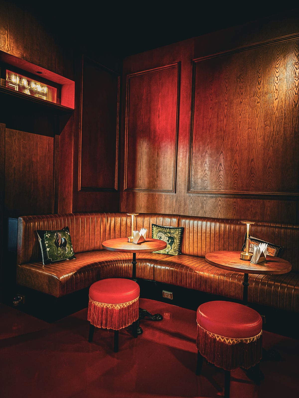 A curved red velvet booth with low lamps and wood-paneled walls