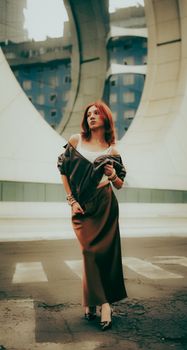 Elegant woman in urban setting under large architectural arch, captivating city fashion.