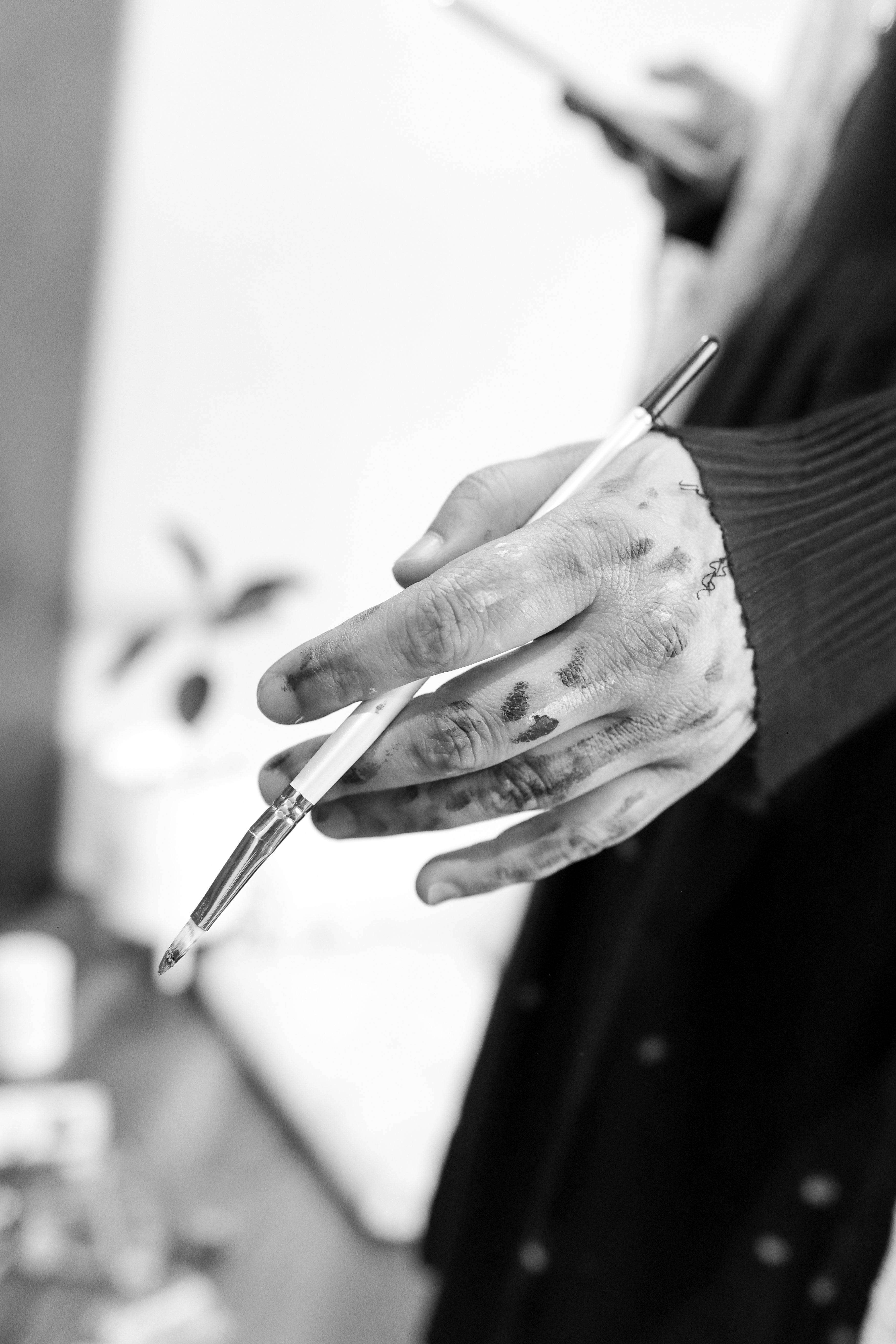 Black and white close-up of an artist's hand holding a paintbrush, conveying creativity and expression.