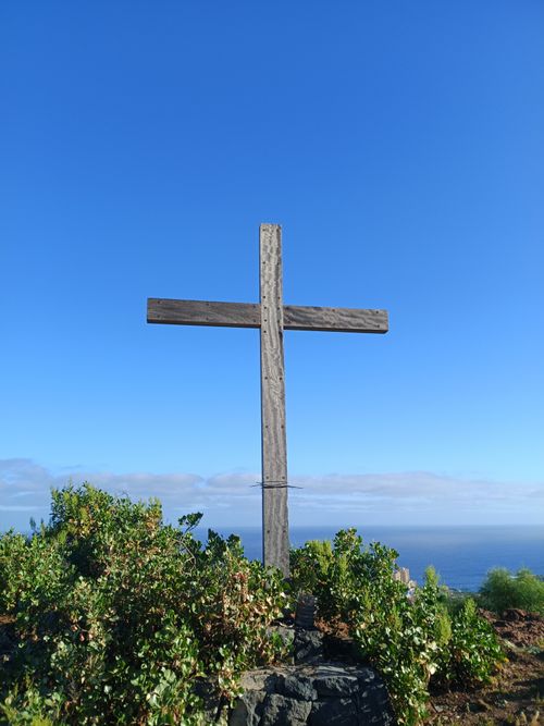Free A wooden cross stands on a cliff in Tenerife with ocean views and blue skies. Stock Photo