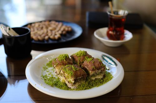 Delicious Turkish dessert topped with pistachios, served with tea in a café setting.