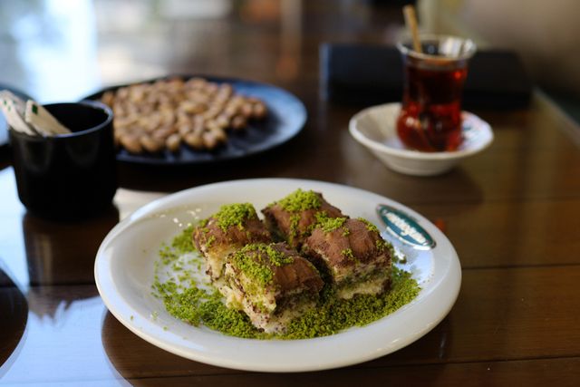 Delicious Turkish dessert topped with pistachios, served with tea in a café setting.
