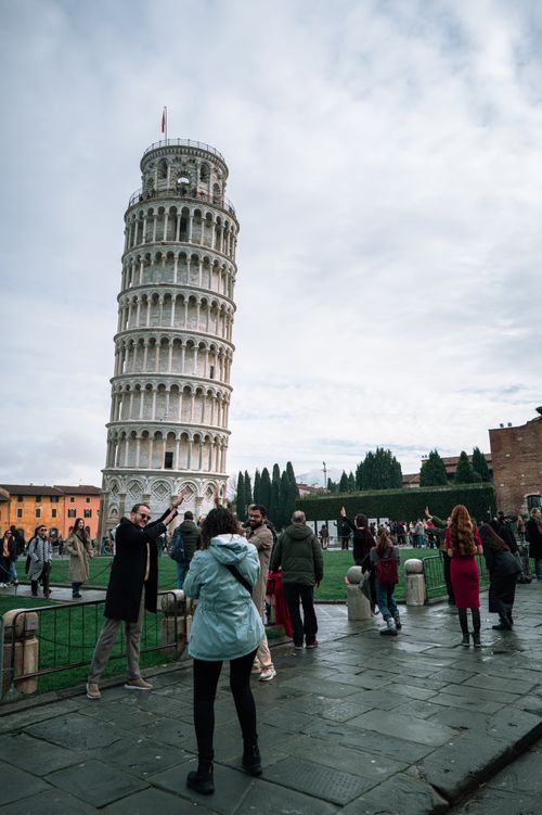 Free Group of tourists at the iconic Leaning Tower of Pisa, capturing memories on a cloudy day. Stock Photo