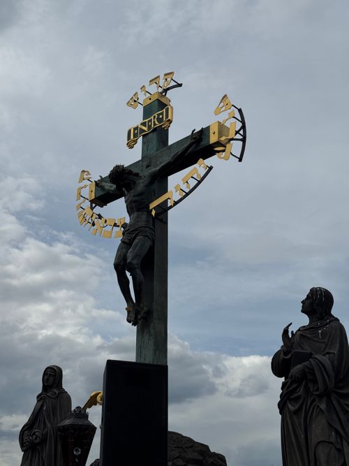 Free Stunning view of the crucifix statue with Jesus Christ on Charles Bridge, Prague, under a cloudy sky. Stock Photo