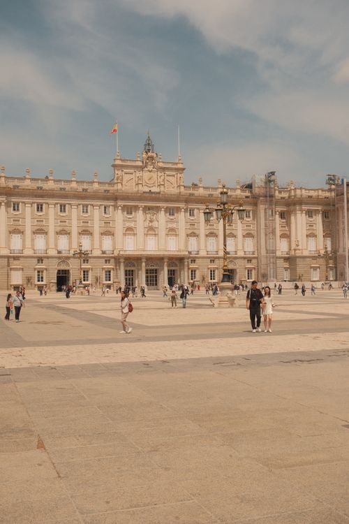 Free Tourists exploring the majestic Royal Palace in Madrid under a bright day sky. Stock Photo