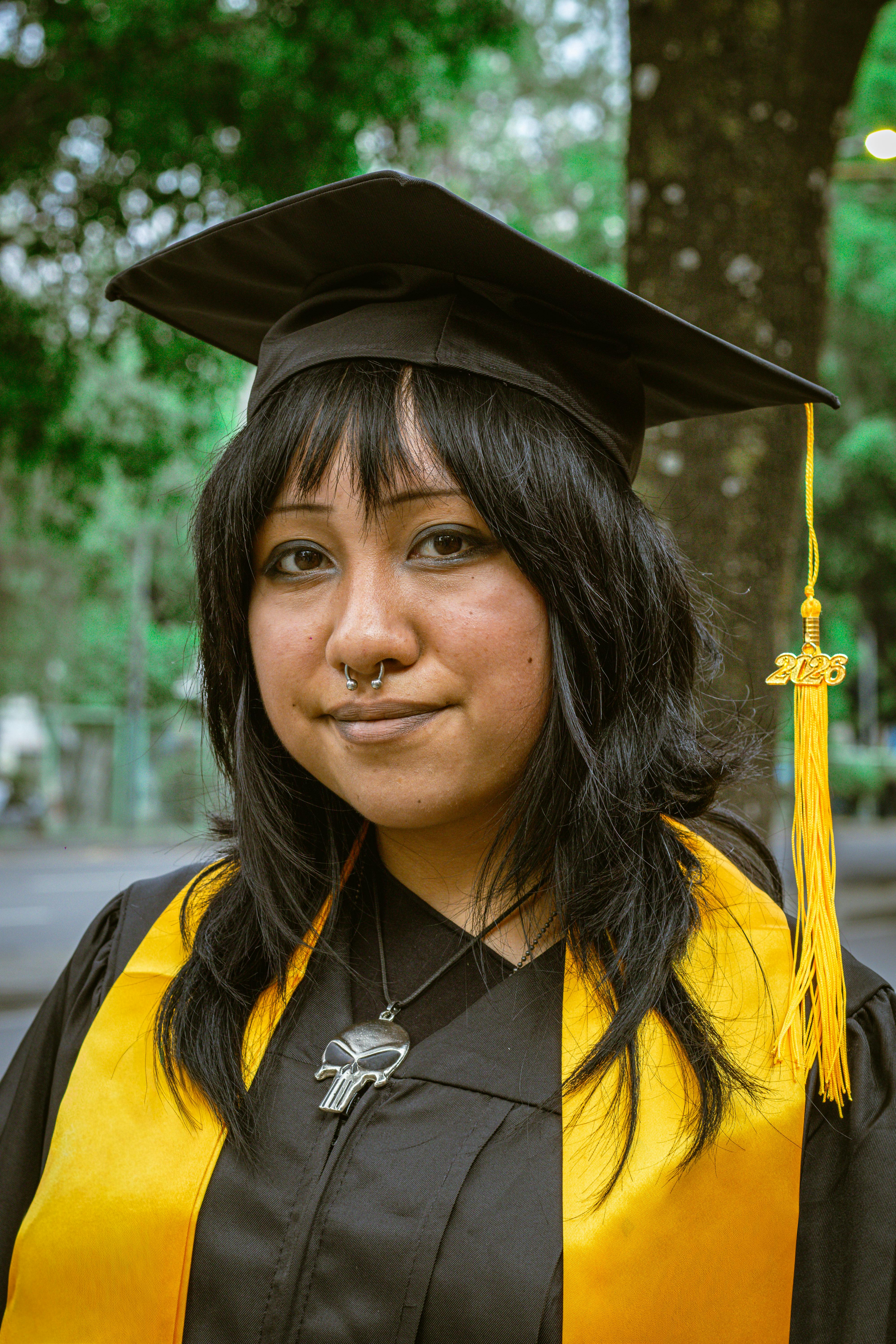 Young Latina woman in graduation gown, outdoors in Ciudad de México, expressing achievement.