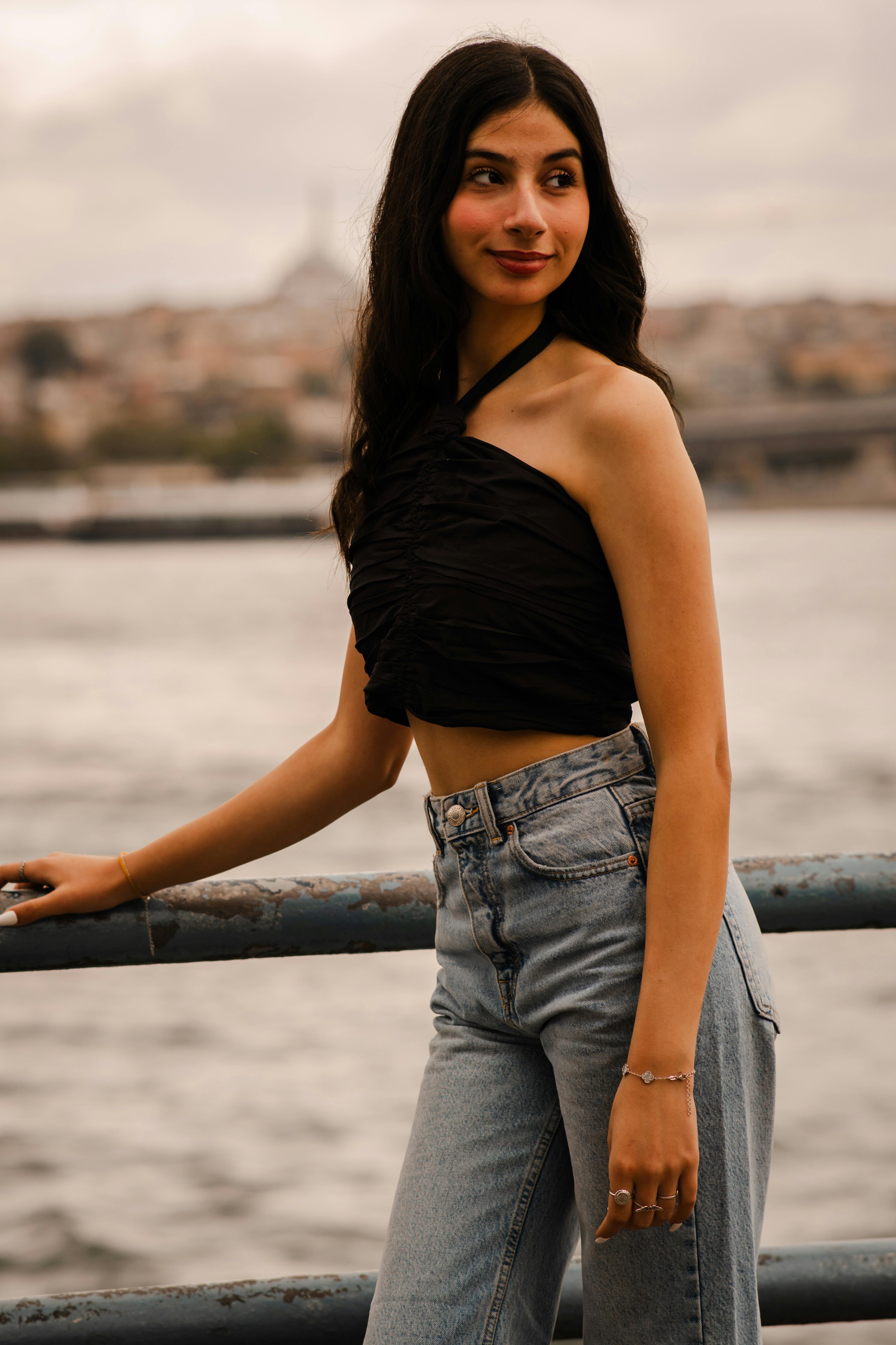 A stylish woman posing by the Bosphorus with Istanbul's skyline in the background.