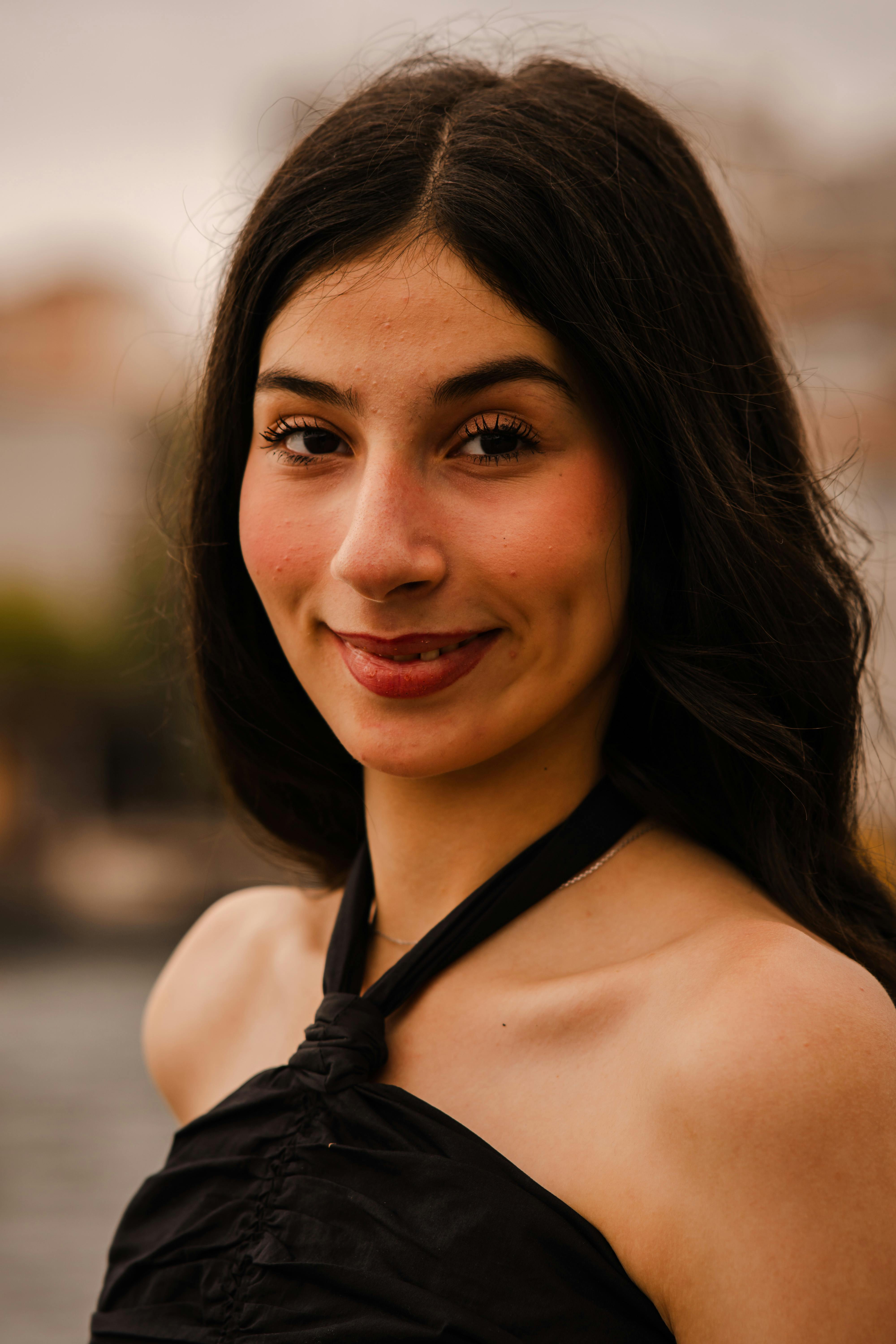 Charming portrait of a young woman during golden hour in Istanbul, capturing her natural smile and cityscape backdrop.
