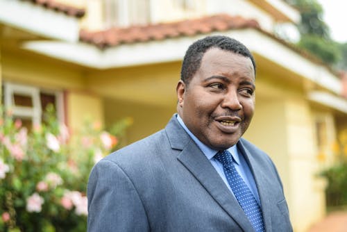 Cheerful black businessman standing near building