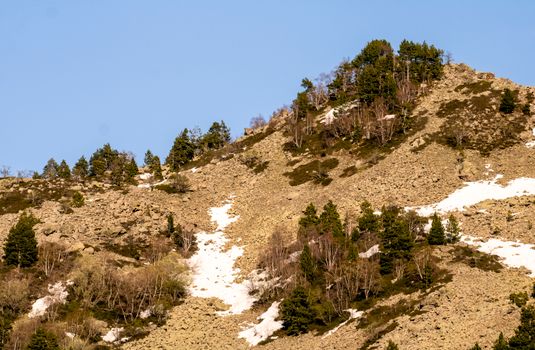Snow-dusted mountainside with sparse trees under a clear sky in Andorra la Vella.