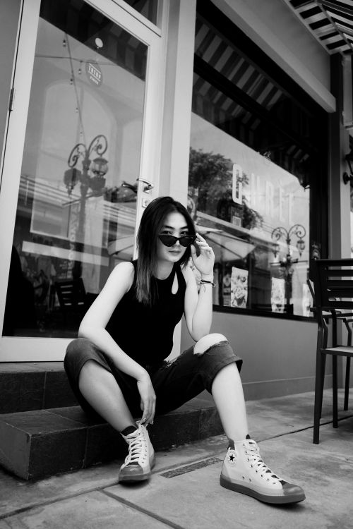 Free Black and white portrait of a fashionable woman sitting outside a cafe. Stock Photo