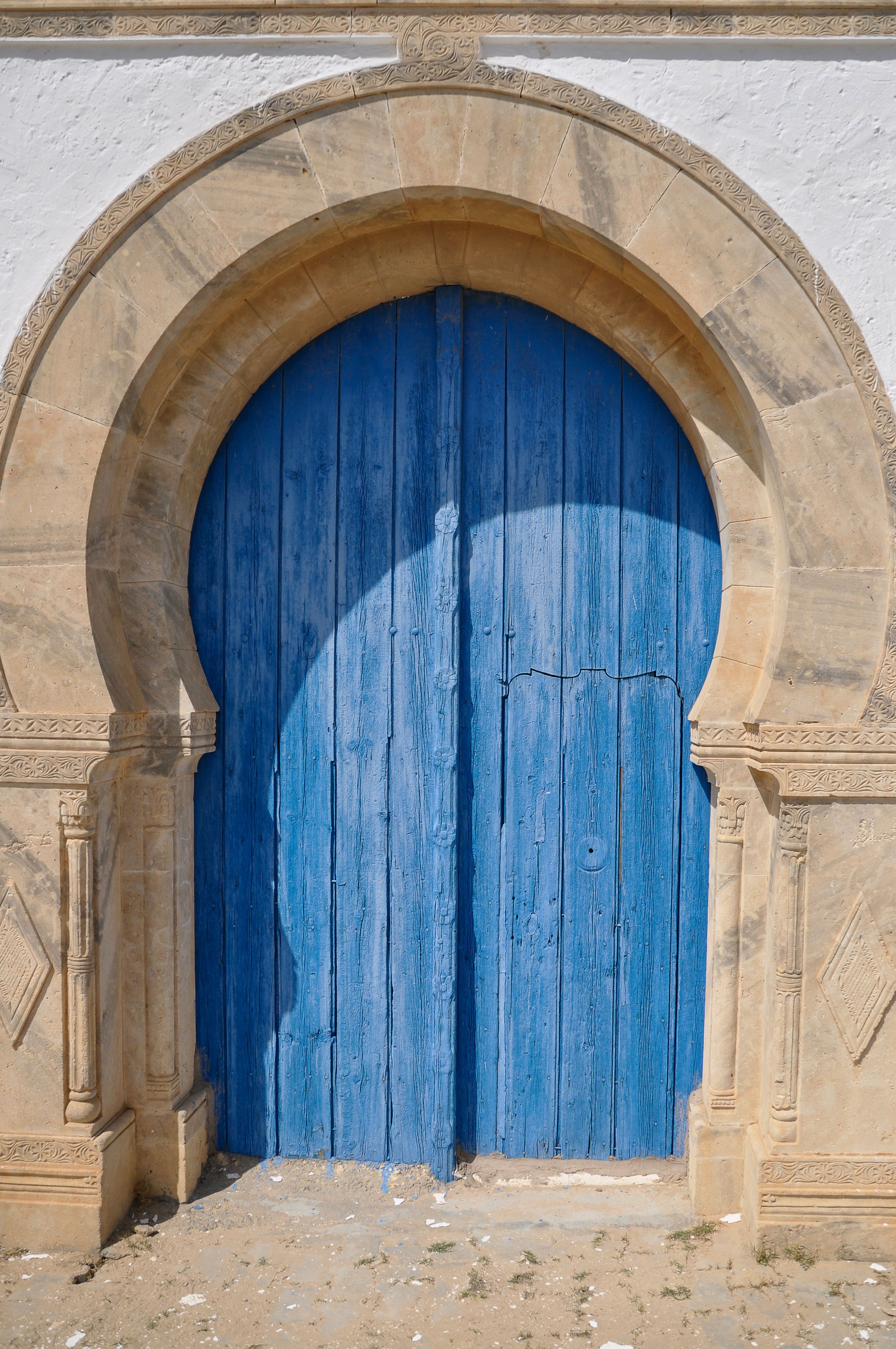 Historic Tunisian stone arch with blue wooden door in Tunis, showcasing traditional architecture.