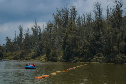 Explore the natural beauty of Ooty Lake with people enjoying a boat ride amidst lush green trees.