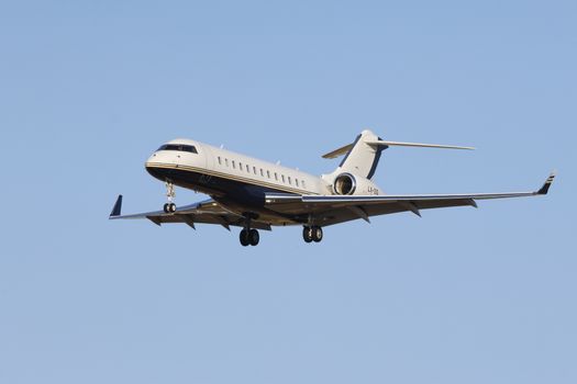 A sleek private jet in mid-flight against a clear blue sky, showcasing luxury aviation.