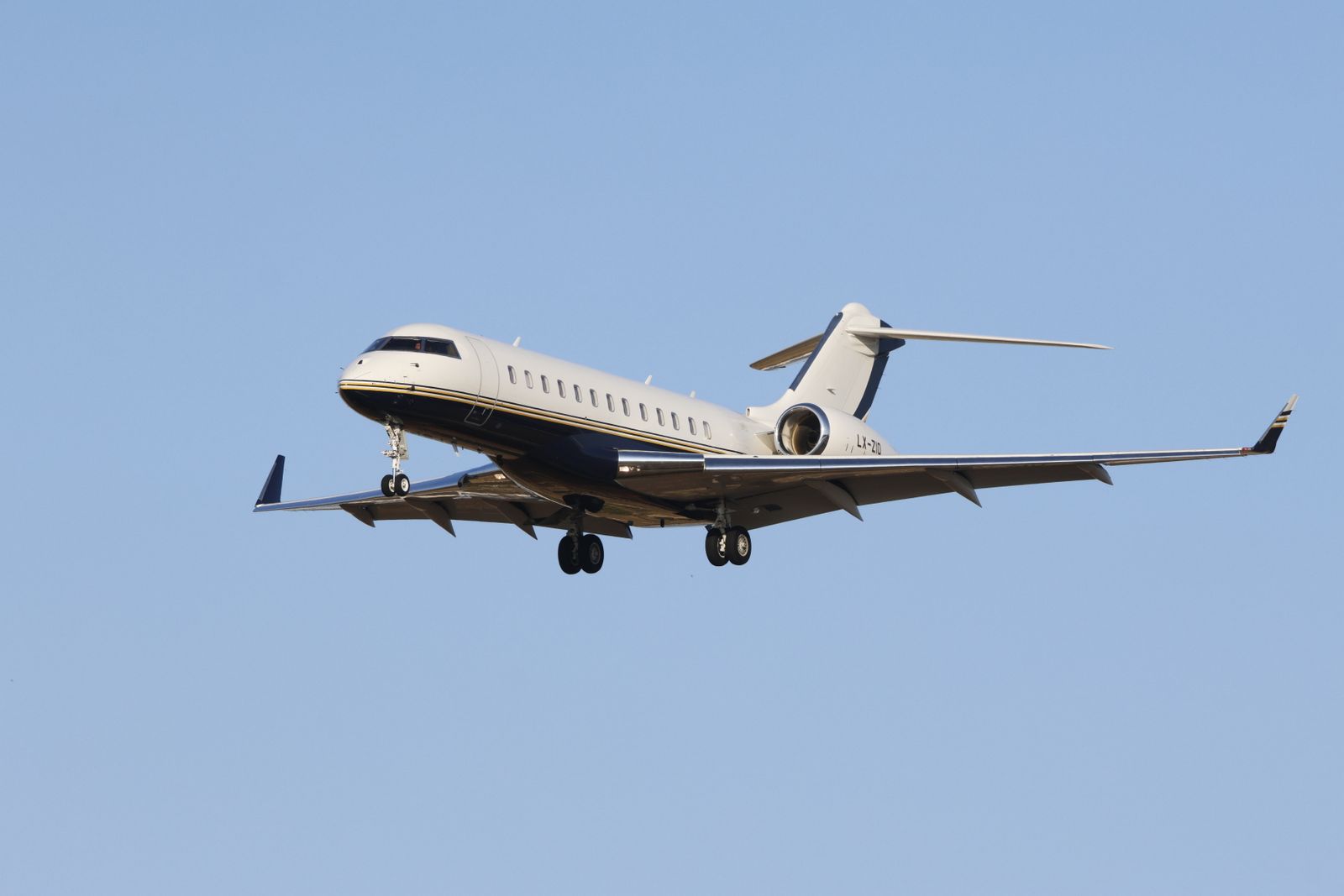 A sleek private jet in mid-flight against a clear blue sky