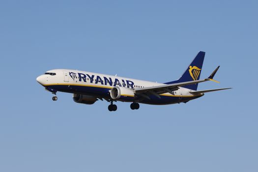 Ryanair airplane flying against a clear blue sky during daytime.