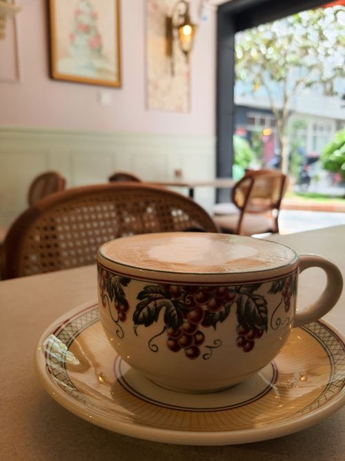 Free Artisan-style cappuccino in a decorative cup set in a warm, inviting café ambiance. Stock Photo