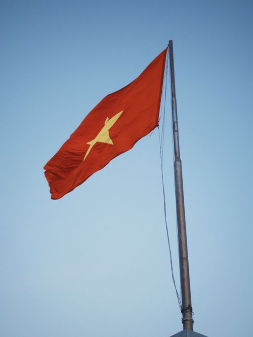 Free Photograph of the Vietnamese national flag waving prominently against a clear blue sky. Stock Photo
