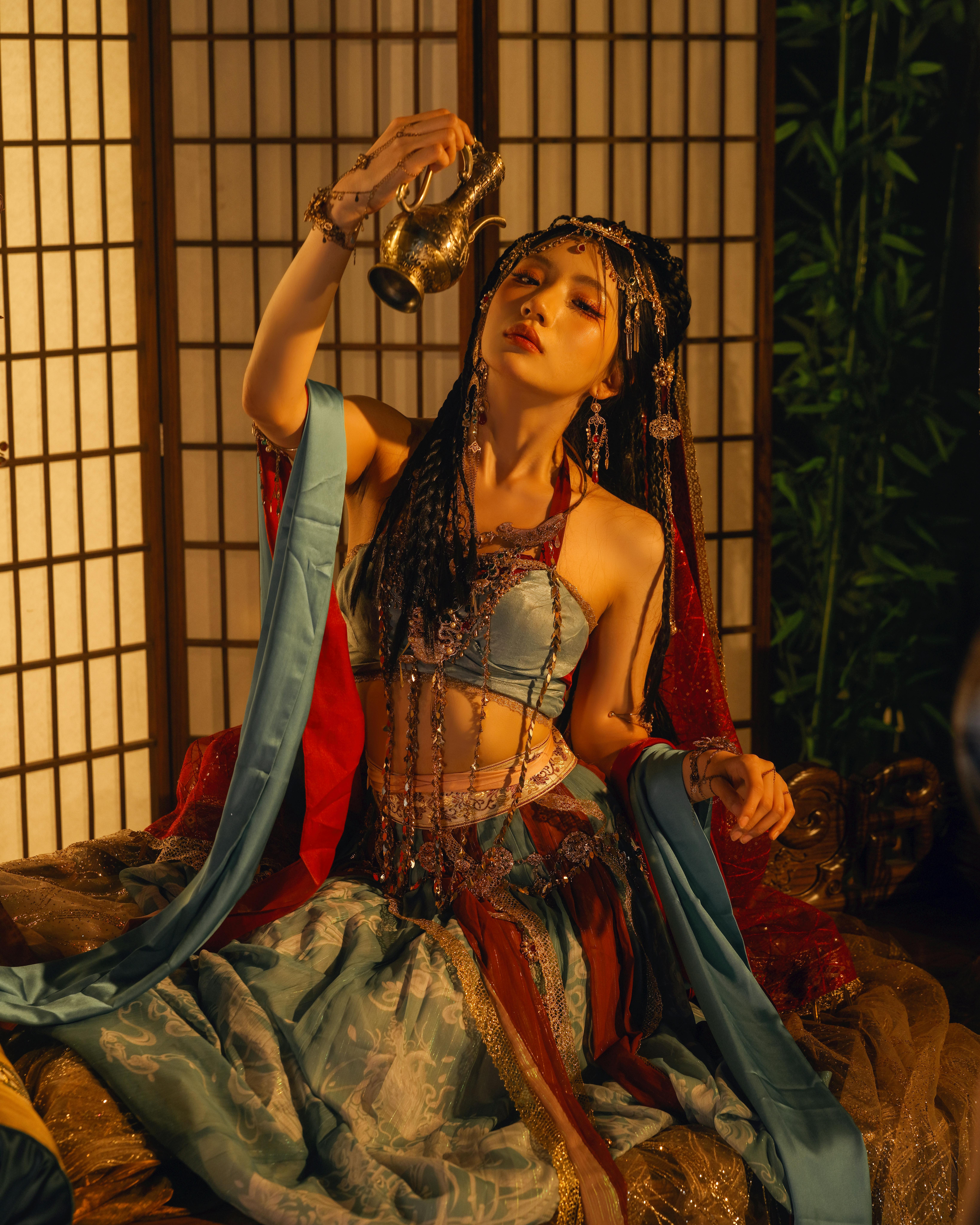 Mesmerizing portrait of a woman in traditional attire holding a decorative teapot. Perfect for cultural themes.