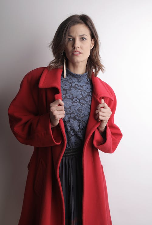 Woman in Red Coat Standing Near White Wall