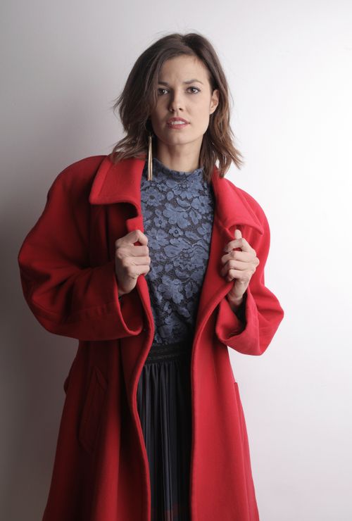 Free Elegant woman in red coat posing in a studio setting, showcasing contemporary fashion. Stock Photo