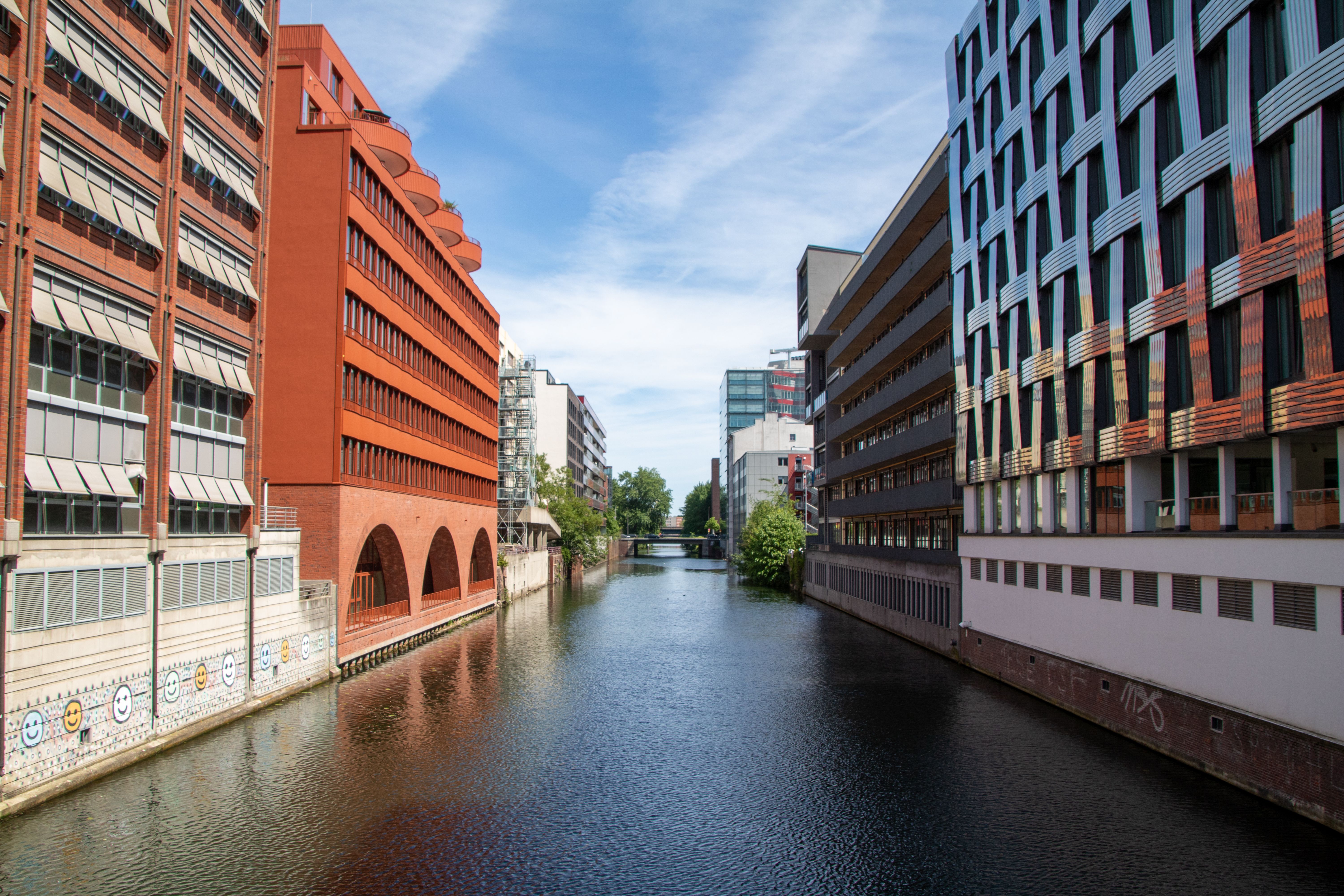 Scenic view of a Hamburg canal with modern architecture under a sunny sky.