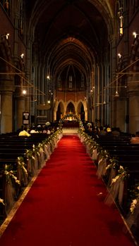 A stunning view of a Gothic church interior adorned for a ceremonial event with flowers and red carpet.