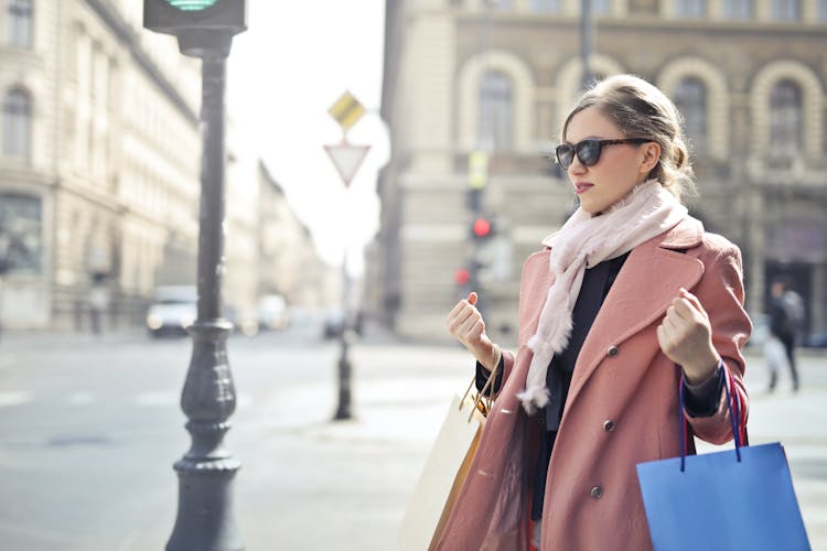 Woman In Pink Coat Holding Shopping Bags