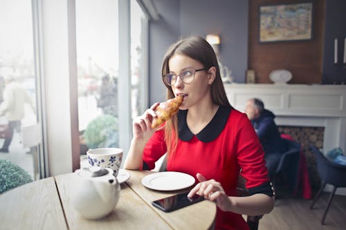 Free Woman Sitting on Wooden Chair Eating Bread Stock Photo