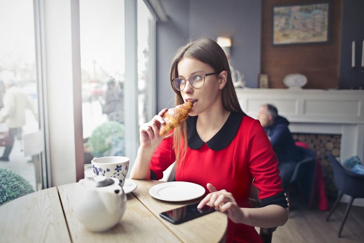 Woman Sitting On Wooden Chair Eating Bread